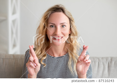 Good luck. Faithful woman. Sincere wish. Pretty inspired hopeful lady crossing fingers asking bless sitting sofa in light room interior. Good luck. Faithful woman. Sincere wish. Pretty inspired hopeful lady crossing fingers asking bless sitting sofa in light room interior. 87510243