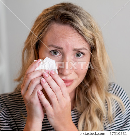 Desperate feelings. Upset woman. Sorrow regret. Sad pretty lady crying mopping tears with napkin sitting sofa in light room interior. Desperate feelings. Upset woman. Sorrow regret. Sad pretty lady crying mopping tears with napkin sitting sofa in light room interior. 87510281