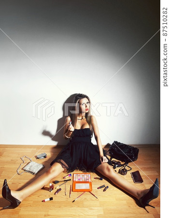 On a beauty mission. A woman sitting on the floor among her makeup products. 87510282