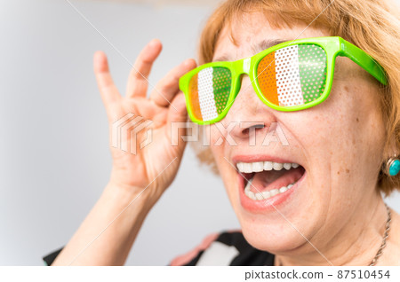 Portrait of smiling elderly woman wearing glasses with ireland flag. Portrait of smiling elderly woman wearing glasses with ireland flag. 87510454