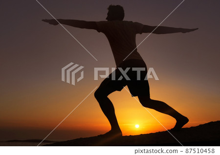 Stretching in the dwindling light. Silhouette of a man doing exercises with the sunset in the background. Stretching in the dwindling light. Silhouette of a man doing exercises with the sunset in the background. 87510458
