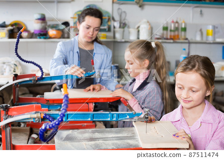 Happy girls practicing skills at wood carving Happy girls practicing skills at wood carving 87511474