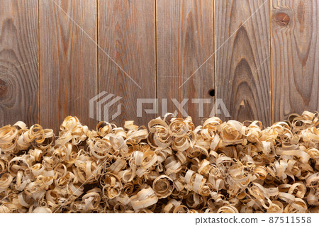 Wood shavings at table background. Wooden shaving on old plank board 87511558