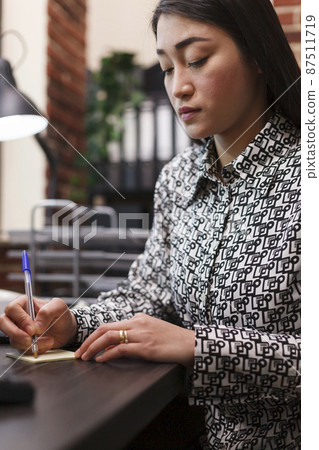 Advertising agency employee writing down client contact information regarding collaboration. 87511719