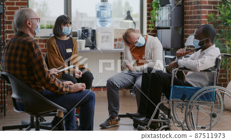 Man with disability attending aa therapy session meeting with people during covid 19 pandemic 87511973
