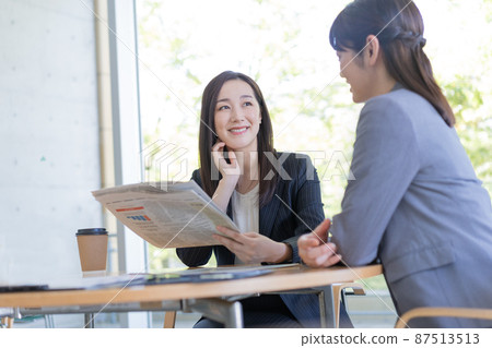商務 兩位商界女性一邊看英文報紙一邊交談 商務 兩位商界女性一邊看英文報紙一邊交談 87513513