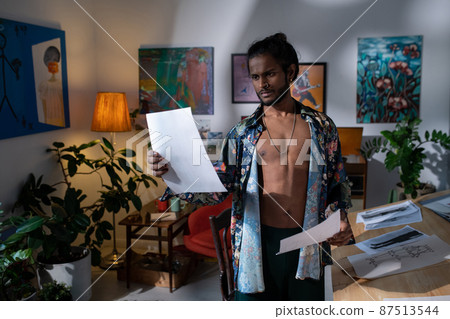 Young serious man in smart casualwear looking through his drawings 87513544
