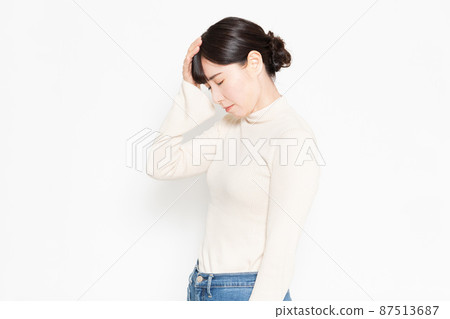 Woman standing in front of white background and making headache gestures Woman standing in front of white background and making headache gestures 87513687