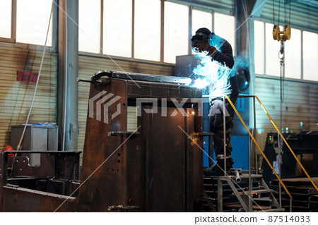 Contemporary worker or welder in protective mask and uniform repairing machine Contemporary worker or welder in protective mask and uniform repairing machine 87514033