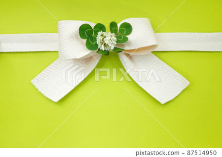 帶有三葉草裝飾的天然絲帶。背景黃綠色 87514950
