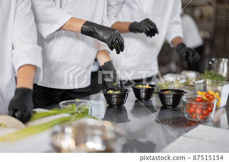 Chefs prepare takeaway food in professional kitchen Chefs prepare takeaway food in professional kitchen 87515154
