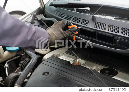 Mechanic man hand checking car engine oil Mechanic man hand checking car engine oil 87515495