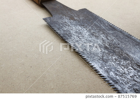 A saw that has rusted and its blade has become tattered 87515769