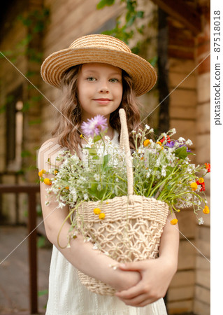 Smiling preteen girl holding wicker basket with colorful wildflowers on summer day Smiling preteen girl holding wicker basket with colorful wildflowers on summer day 87518018