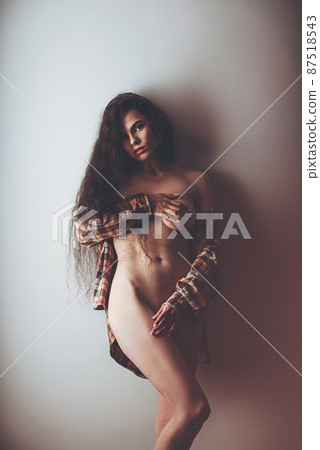 Emotional studio portrait of a young woman in a wireless headphones and checkered shirt 87518543