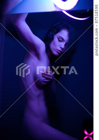 Emotional studio portrait of a young woman in a wireless headphones with ring flash effect. Round LED Circle Lamp. 87518598