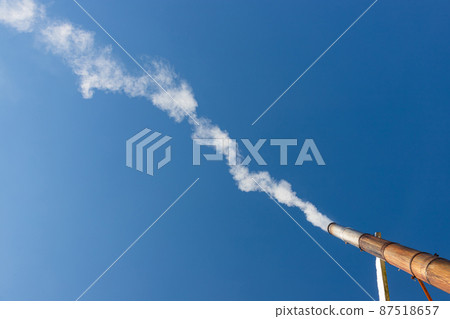 a plume of smoke or steam from an industrial smokestack on a clear blue sky 87518657