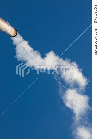 a plume of smoke or steam from an industrial smokestack on a clear blue sky 87518658