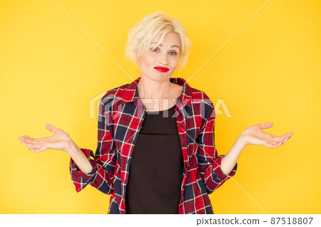Shrugging hands. Skeptic woman. Unsure emotion. Puzzled hesitating casual middle-aged lady holding arms up looking clueless isolated yellow. Shrugging hands. Skeptic woman. Unsure emotion. Puzzled hesitating casual middle-aged lady holding arms up looking clueless isolated yellow. 87518807