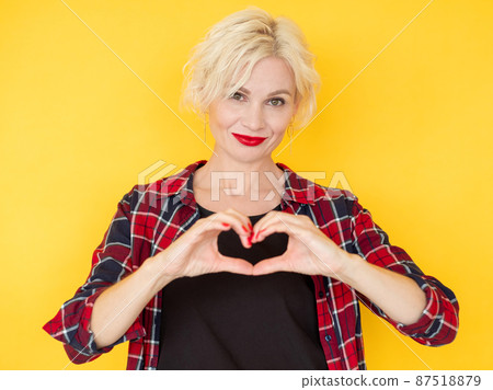 Love care. Affected woman. Feelings expression. Happy middle-aged lady holding hands forming heart shape gesture isolated yellow. Love care. Affected woman. Feelings expression. Happy middle-aged lady holding hands forming heart shape gesture isolated yellow. 87518879