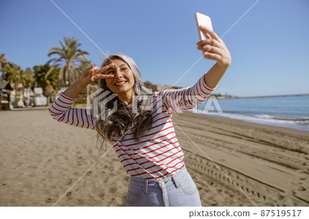 Happy urban woman relaxing outdoors by sea Happy urban woman relaxing outdoors by sea 87519517