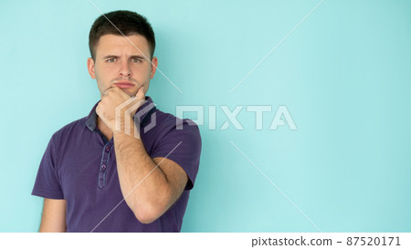 Problem considering. Thoughtful man. Find solution. Puzzled handsome guy in casual t-shirt holding hand on chin isolated blue copy space. Problem considering. Thoughtful man. Find solution. Puzzled handsome guy in casual t-shirt holding hand on chin isolated blue copy space. 87520171