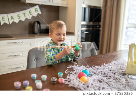 Focused creative boy decorating eggs for Easter 87520386