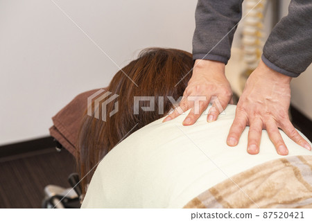 A woman receiving massage (bodywork, pelvic correction) 87520421