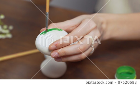 Close-up of a woman's hands painting an easter egg with a paintbrush. Church holiday-Easter Close-up of a woman's hands painting an easter egg with a paintbrush. Church holiday-Easter 87520688