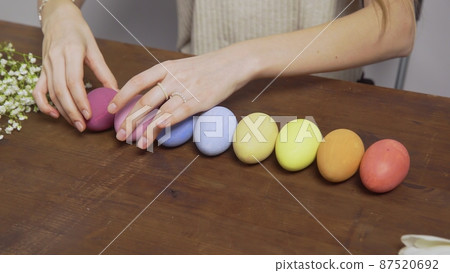 Close-up on a table with colorful Easter eggs. Women's hands lay eggs on the table. Church holiday-Easter Close-up on a table with colorful Easter eggs. Women's hands lay eggs on the table. Church holiday-Easter 87520692