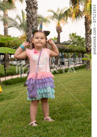 Portrait of a 4 year old girl dressed in a rainbow dress and a unicorn headband against the backdrop Portrait of a 4 year old girl dressed in a rainbow dress and a unicorn headband against the backdrop 87521653