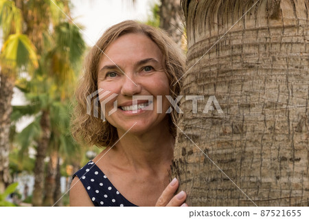 Portrait of a mature woman 50-60 years old against the backdrop of palm trees Portrait of a mature woman 50-60 years old against the backdrop of palm trees 87521655