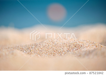 Close up of clean yellow sand surface covering seaside beach with blue sea water on background. Travel and vacations concept. Close up of clean yellow sand surface covering seaside beach with blue sea water on background. Travel and vacations concept. 87521842