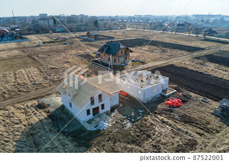Aerial view of unfinished frame of private house with aerated lightweight concrete walls and wooden roof frame under construction. Aerial view of unfinished frame of private house with aerated lightweight concrete walls and wooden roof frame under construction. 87522001