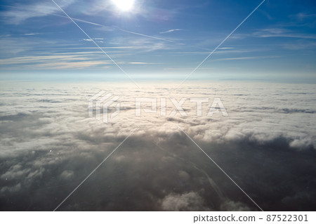 Aerial view from airplane window at high altitude of distant city covered with layer of thin misty smog and distant clouds in evening Aerial view from airplane window at high altitude of distant city covered with layer of thin misty smog and distant clouds in evening 87522301