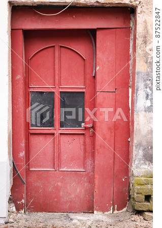 Red wooden door with glass in aged concrete building wall Red wooden door with glass in aged concrete building wall 87522847