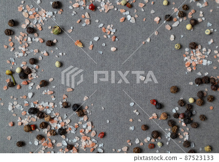 Crystals of pink salt and spices from black, white and pink pepper on a dark background with space for your text. Pattern. 87523133