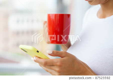 A young brunette woman looks at the mobile phone screen A young brunette woman looks at the mobile phone screen 87523592