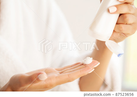 Smiling young woman applying moisture face cream. Smiling young woman applying moisture face cream. 87523656
