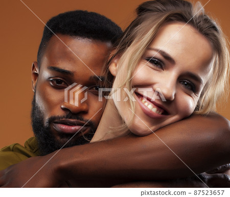 Young pretty couple diverse races together posing sensitive on brown background, lifestyle people concept Young pretty couple diverse races together posing sensitive on brown background, lifestyle people concept 87523657