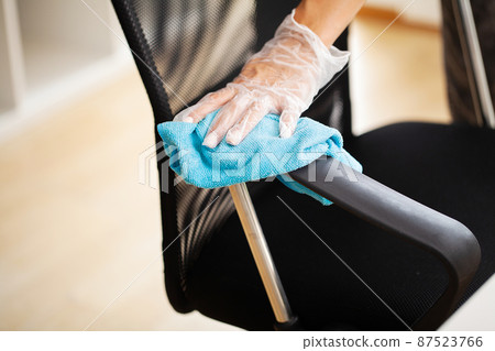 Woman wipes furniture in the office with a damp disinfectant wipe 87523766