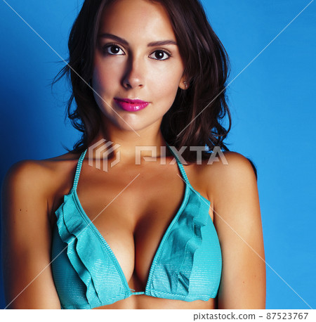 young pretty brunette girl in bikini smiling studio blue background, lifestyle people concept 87523767