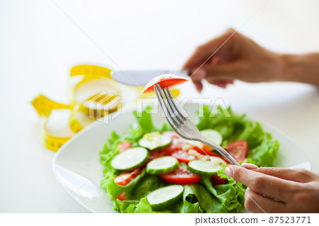 Woman choosing between junk burger and fresh salad 87523771