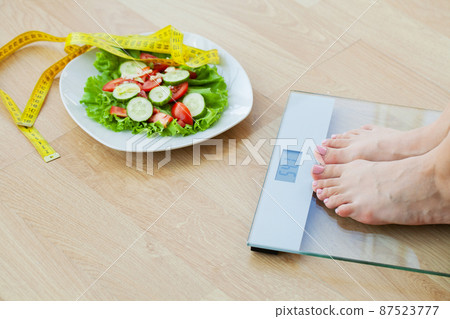 Woman choosing between junk burger and fresh salad 87523777