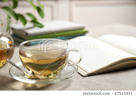 Tasty hot green tea in cup on grey table Tasty hot green tea in cup on grey table 87523851