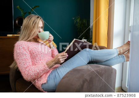 A girl relaxes by reading a book and drinking coffee. A girl relaxes by reading a book and drinking coffee. 87523908