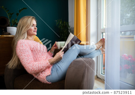 A girl reads a book with a cup in her hand while resting. A girl reads a book with a cup in her hand while resting. 87523911