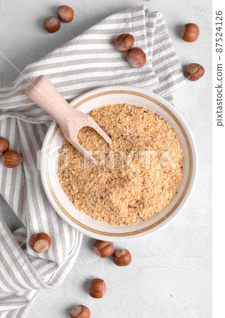 Raw Organic Ground Hazelnut Flour in a Bowl with whole nuts on grey stone background. Alternative nut flour Raw Organic Ground Hazelnut Flour in a Bowl with whole nuts on grey stone background. Alternative nut flour 87524126