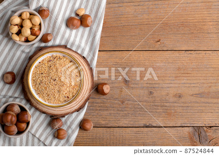 Raw Organic Ground Hazelnut Flour in a Bowl with whole nuts on rustic wooden background. Alternative nut flour Raw Organic Ground Hazelnut Flour in a Bowl with whole nuts on rustic wooden background. Alternative nut flour 87524844
