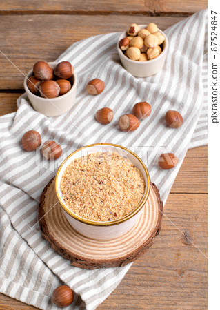 Raw Organic Ground Hazelnut Flour in a Bowl with whole nuts on rustic wooden background. Alternative nut flour Raw Organic Ground Hazelnut Flour in a Bowl with whole nuts on rustic wooden background. Alternative nut flour 87524847
